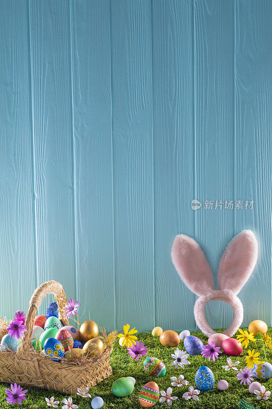 草坪上的复活节彩蛋篮子和蓝色的木墙，春天的花朵