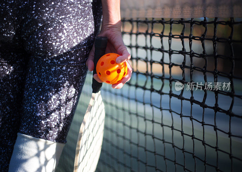 皮克尔球和球拍在女人的手特写，网在背景