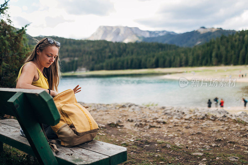 一位美丽的金发女子徒步旅行后坐在木凳上休息。