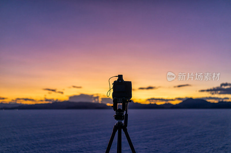 博纳维尔盐滩附近的盐湖城，犹他州在日落后的五彩暮色与紫色和黄色的天空和三脚架相机做延时摄影作为摄影师的pov