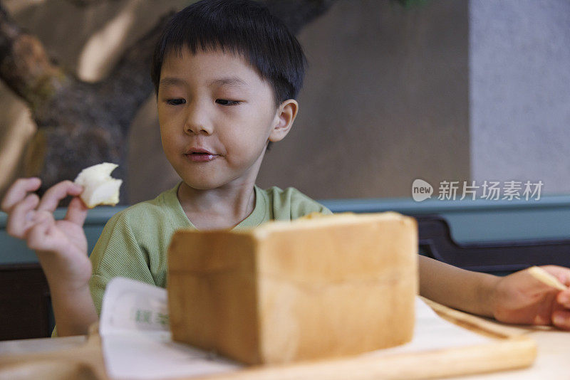 那个亚洲小男孩正在开心地吃面包