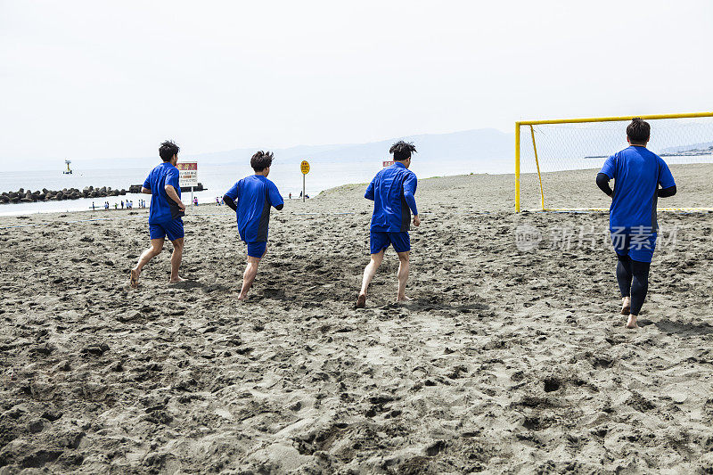 四名球员在沙滩球场慢跑