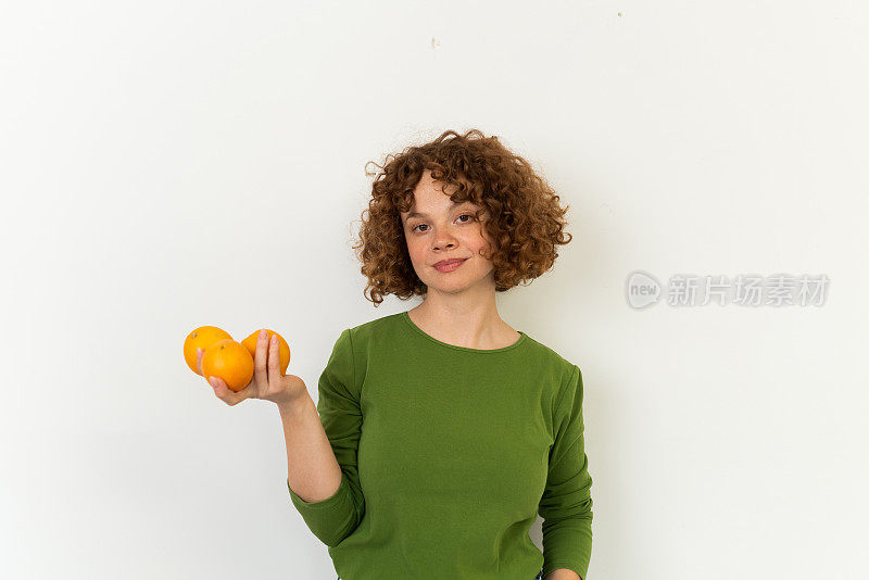 一个美丽的红发女孩的工作室肖像拿着橘子