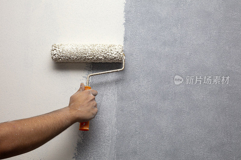 家庭油漆工正在用油漆滚筒刷墙