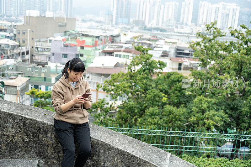 一名女游客在公园平台上休息看她的手机