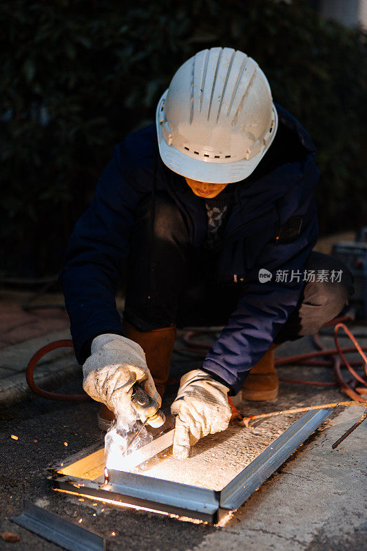 一名中年男性工人正在使用切割机和焊机