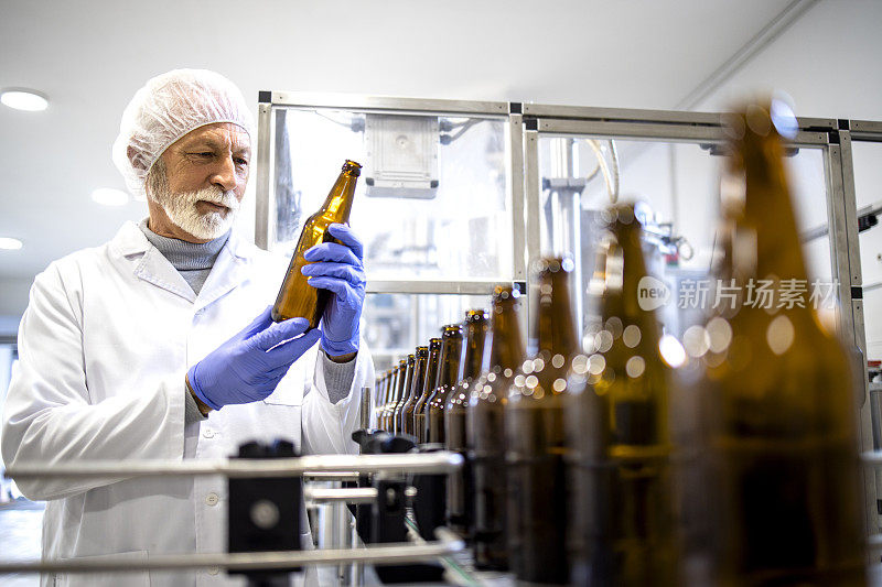 啤酒生产厂和有经验的工人在灌装前检查玻璃瓶。