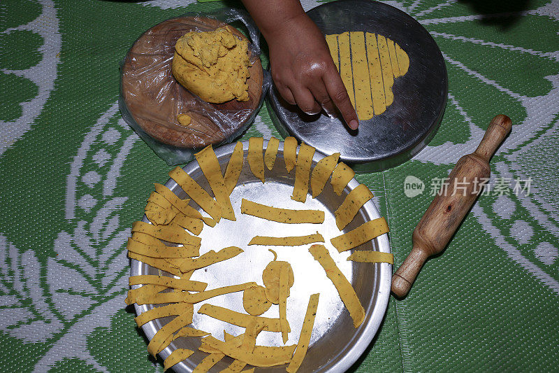 用擀面杖和面团切成条状。自制印度小吃的制作过程。