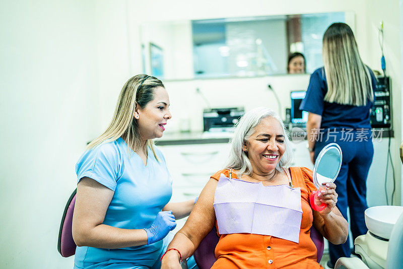 一个成熟的女人在牙医诊所用镜子看自己的牙齿
