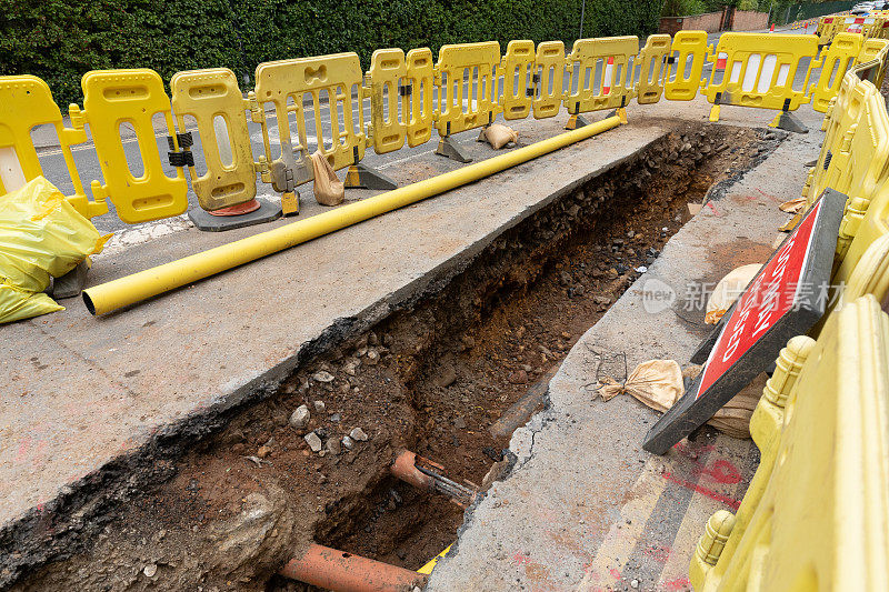 英国的道路工程正在挖掘当地的柏油路面，以修复地下的公用管道，并设置安全屏障和标志