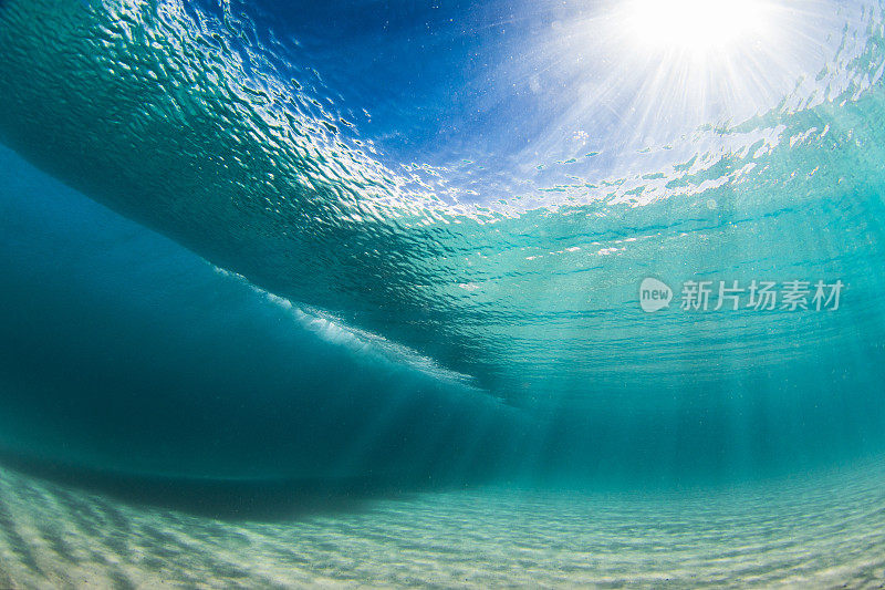 在清澈的海水中，海浪拍打着沙滩，水下的景色一览无余