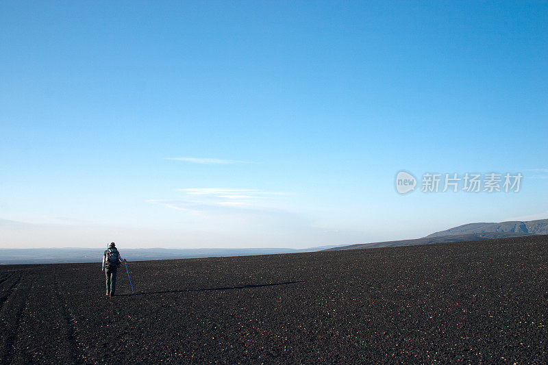 背包客在黑色的熔岩地面上行走