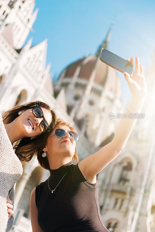 两名美女在匈牙利议会大厦附近拍摄游客自拍