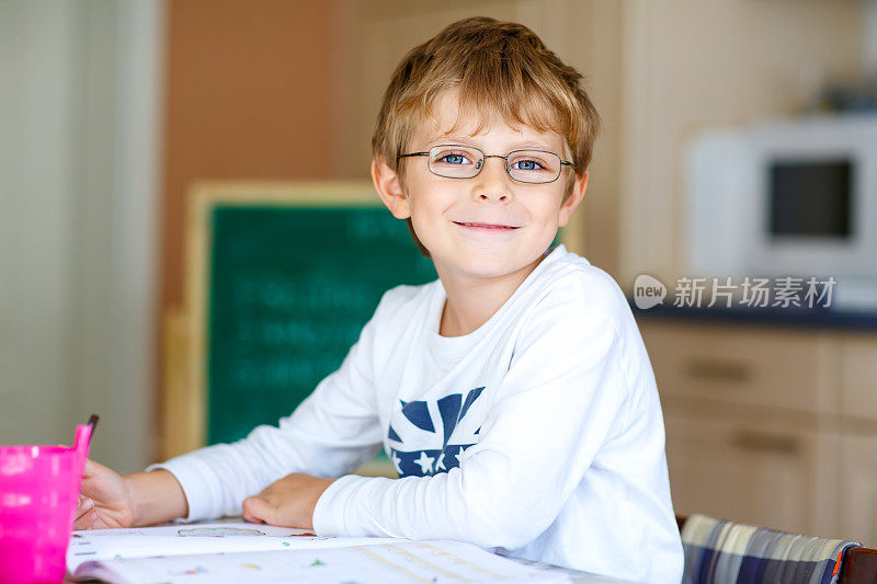 快乐的小学生戴着眼镜在家里做作业