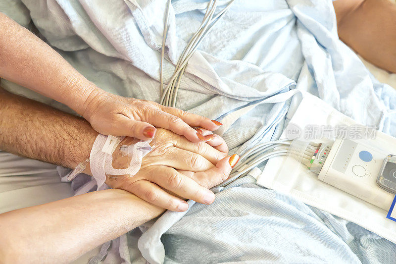一个女人在医院里牵着她丈夫的手。