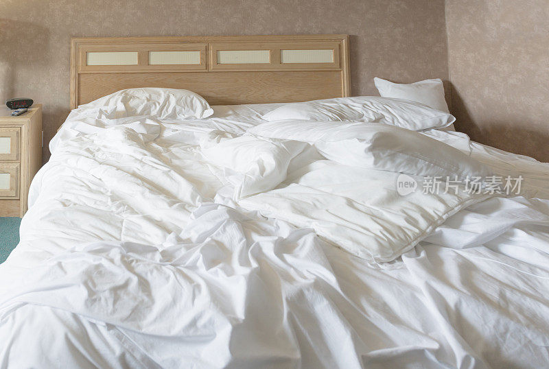 铺满床单和枕头的未整理的床