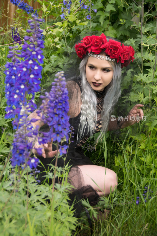 舞者打扮成邪恶的皇后躲在夏天的花园里。
