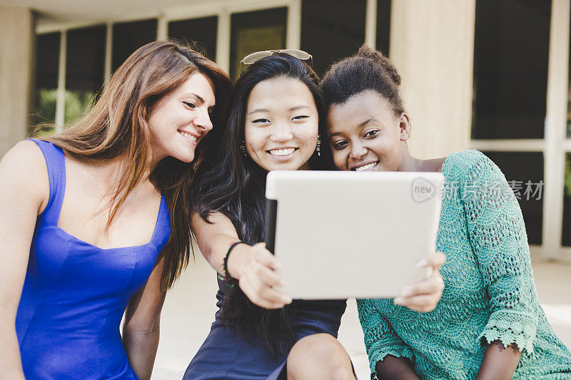 三位年轻女性正在用平板电脑自拍