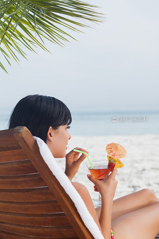 在大海前喝鸡尾酒的女人