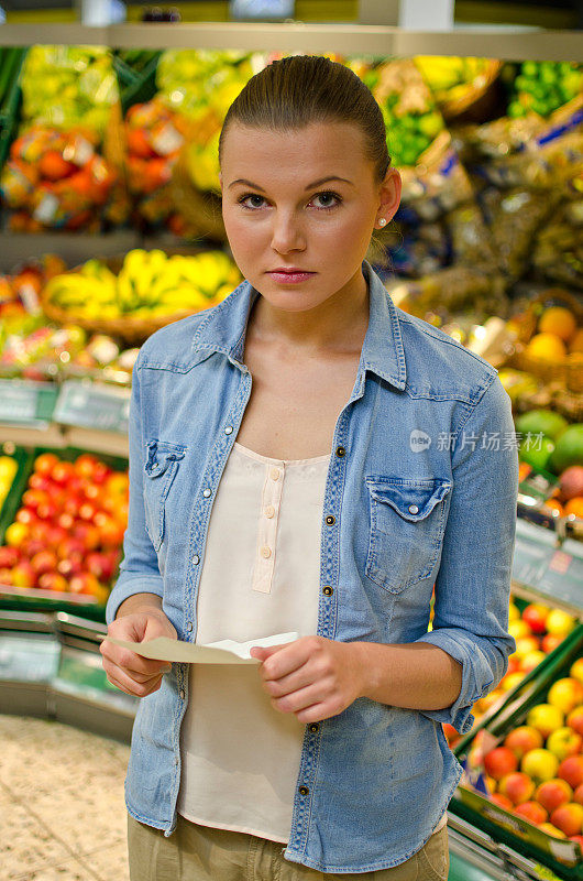 年轻女子在超市拿着一张待做清单