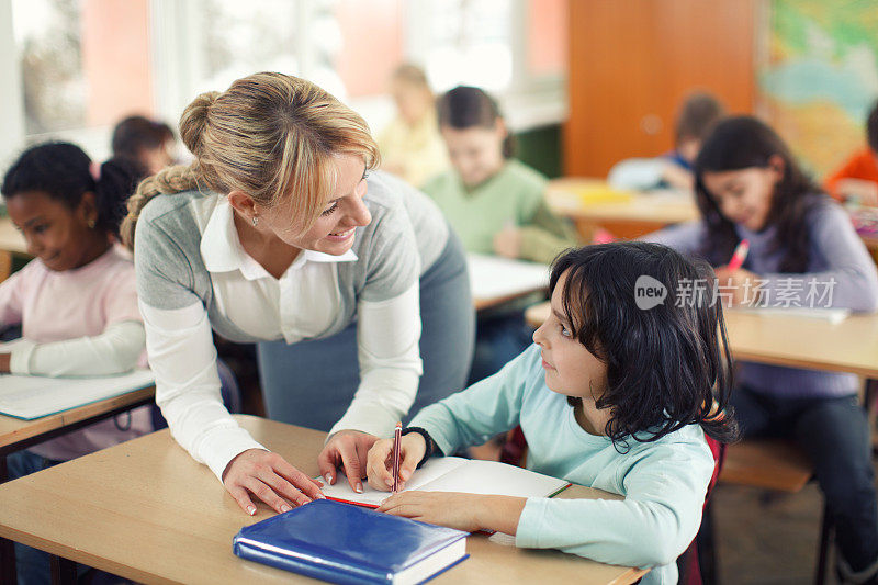 微笑的老师在教室协助学生。