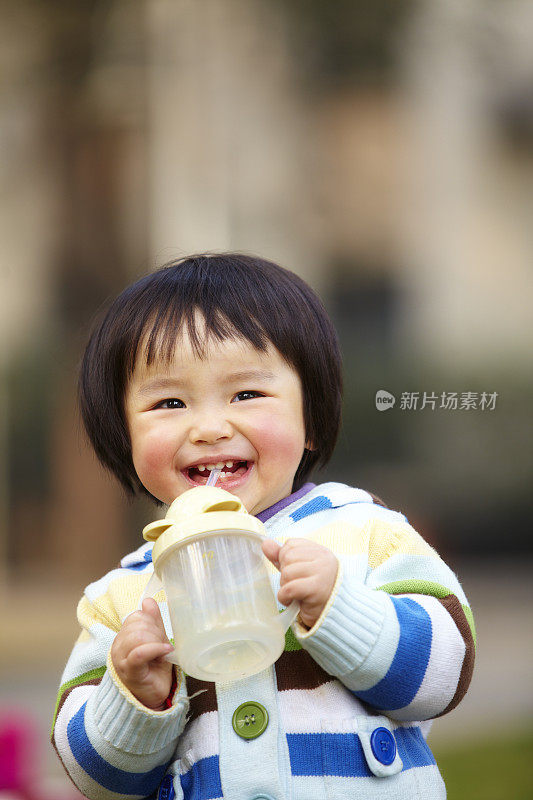 可爱的亚洲小女孩从瓶子里喝水