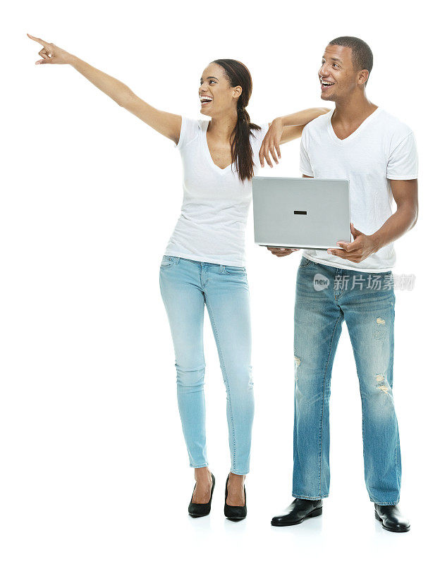幸福的夫妇拿着笔记本电脑，指着别处