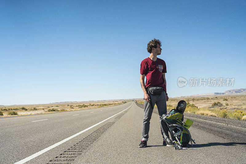 年轻人，搭便车的人，想在犹他州沙漠的高速公路上搭车