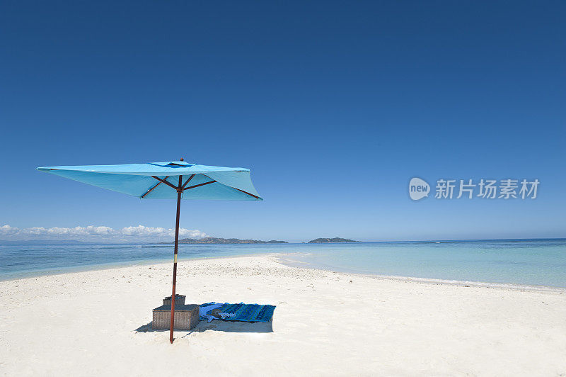 荒无人烟的海滩上的雨伞和野餐篮