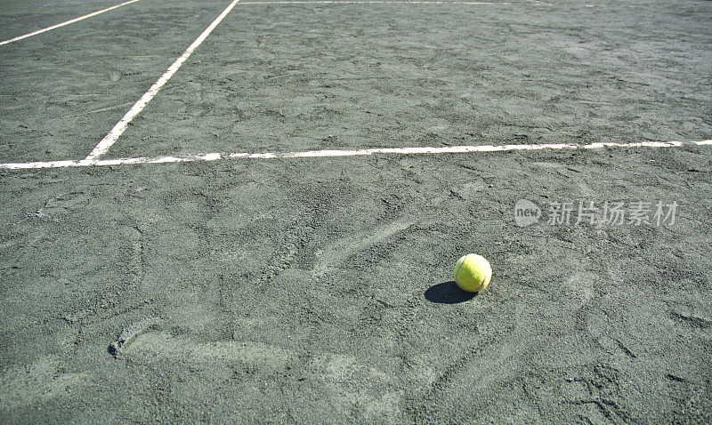 有球和白色边界线的绿粘土网球场