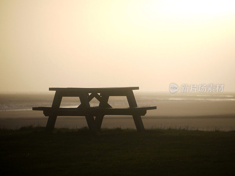 阳光照耀下的海滩野餐长椅