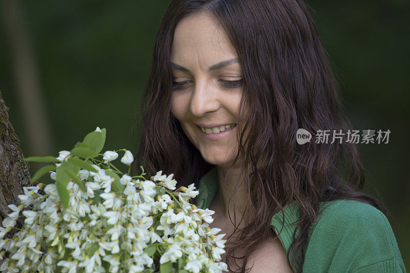 美丽的浅肤色女孩的肖像微笑旁边的一束白色的金合欢花