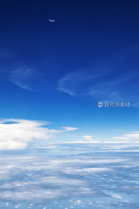 飞机在云层上方的半空中飞行。晴朗的天空背景