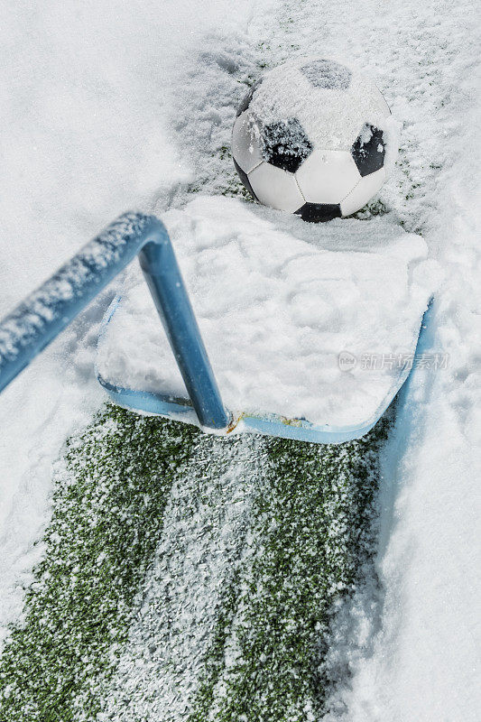 雪铲清理雪旁边的足球被雪覆盖，坐在院子里的一条线