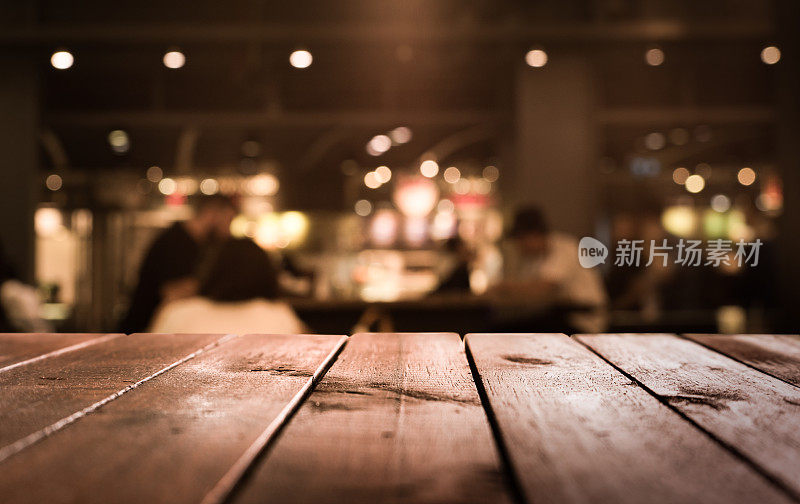 木质桌子与模糊的灯光在晚上的咖啡馆，餐厅背景