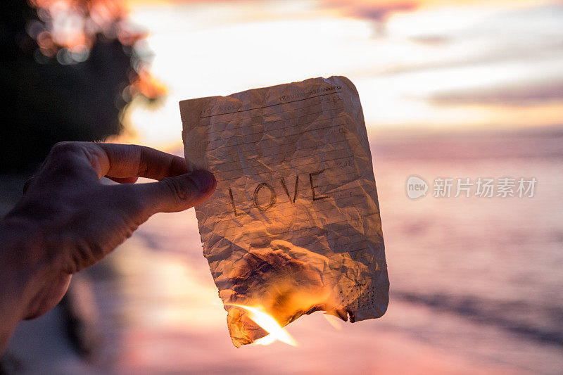 手握着写着爱的燃烧纸