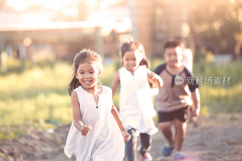 快乐的亚洲孩子有乐趣，一起跑和玩在宇宙花田