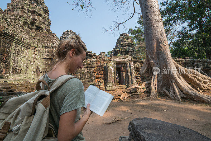 年轻女子在柬埔寨的古庙里阅读旅游指南