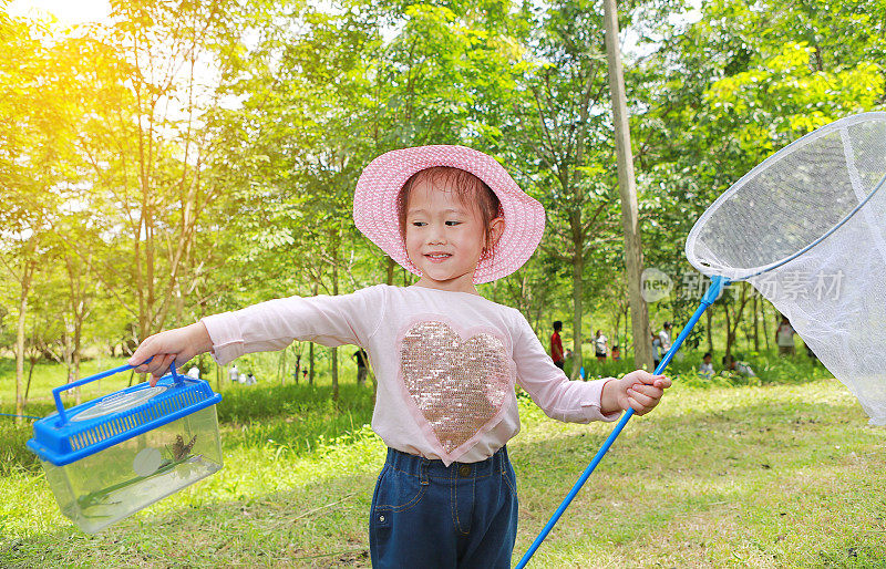 亚洲女孩戴着草帽，戴着蚊帐在地里玩耍。