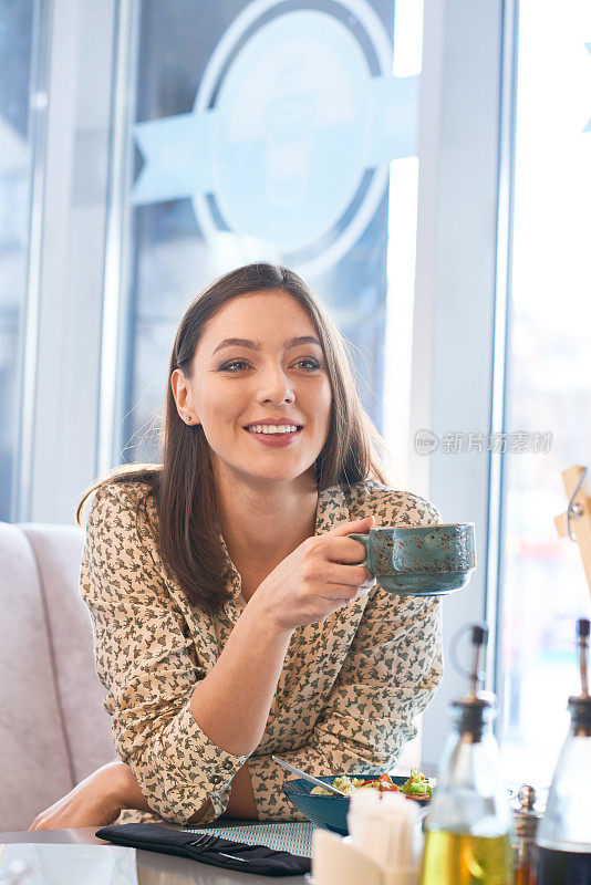 微笑的女人享受着咖啡