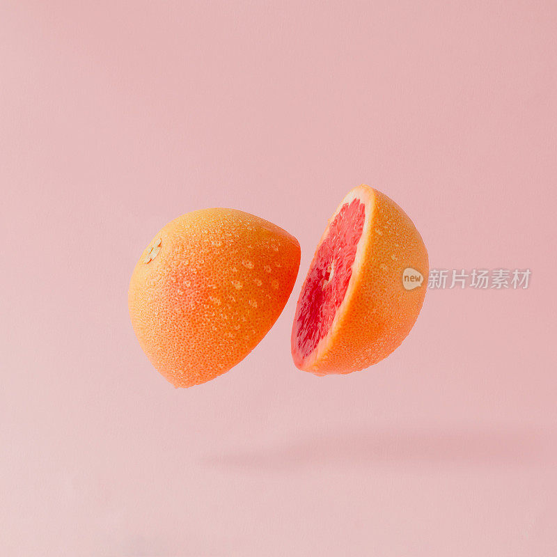 柚子切片，背景为淡粉色。最小的水果的概念。