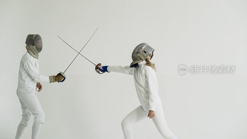 年轻女子击剑训练与教练在室内白色工作室