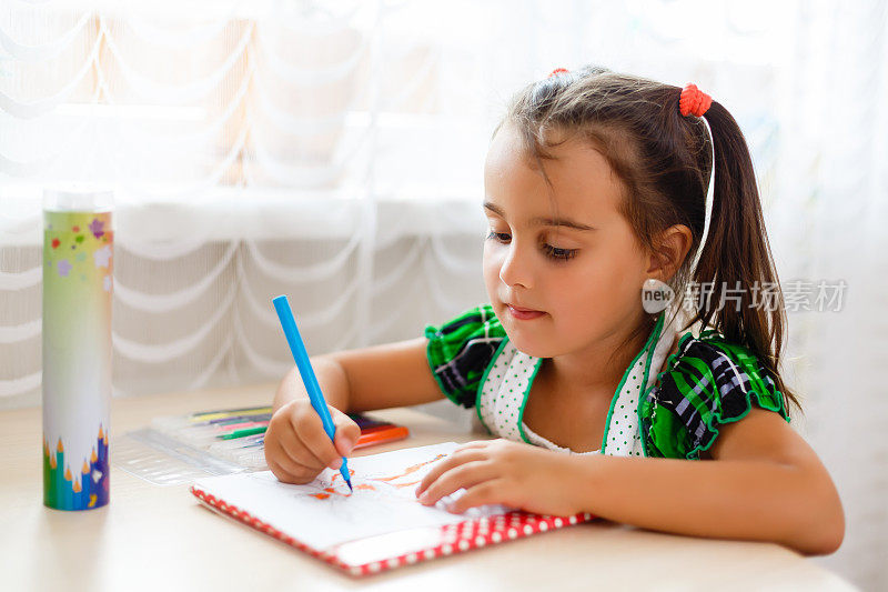 快乐可爱的小女孩做学校作业，在家里的客厅学习，写英语课的笔记本学习知识。