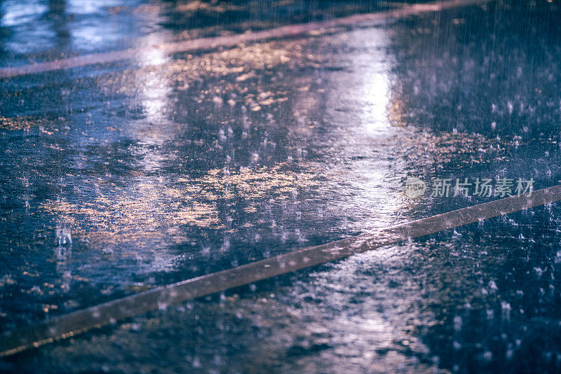 五颜六色的灯光在雨中潮湿的沥青上反射