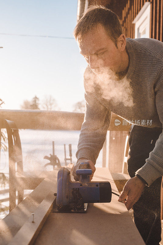 在寒冷的冬天，人们在室外锯木头，做木工