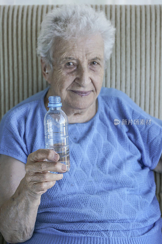 老妇人拿着一瓶饮用水