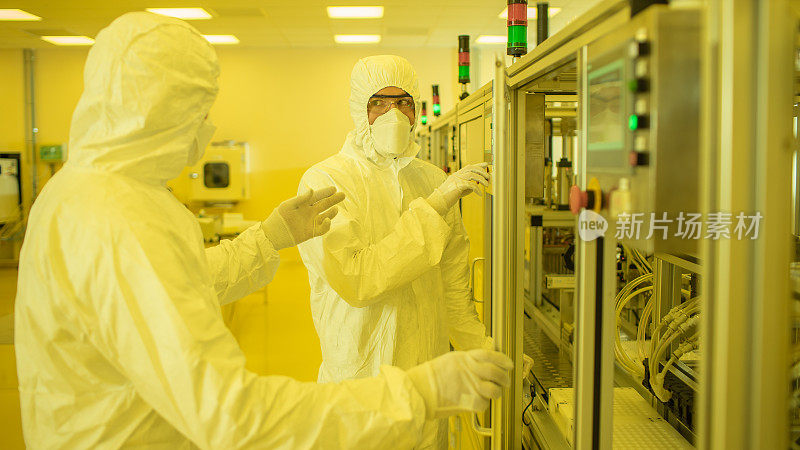 一组科学家穿着无菌防护服在现代工业3D打印机器上工作。制药、生物技术和半导体制造工艺。黄色的过滤器。