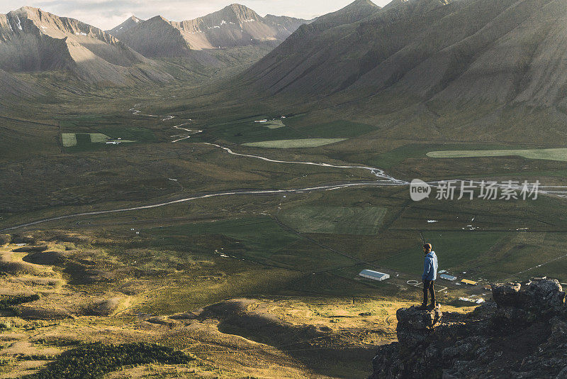 穿着蓝色雨衣的男人看着峡湾的风景