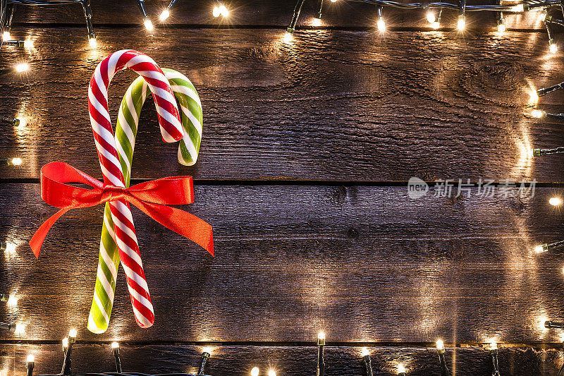 圣诞背景:两根拐杖糖放在质朴的木桌上
