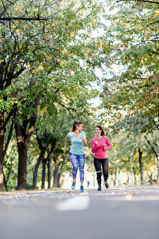 两个女性朋友在阳光公园的小路上慢跑